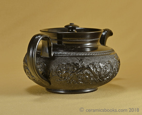 Small low-round black basalt teapot with floral sprig frieze on gauze background, marked CYPLES. Back. AP/1005