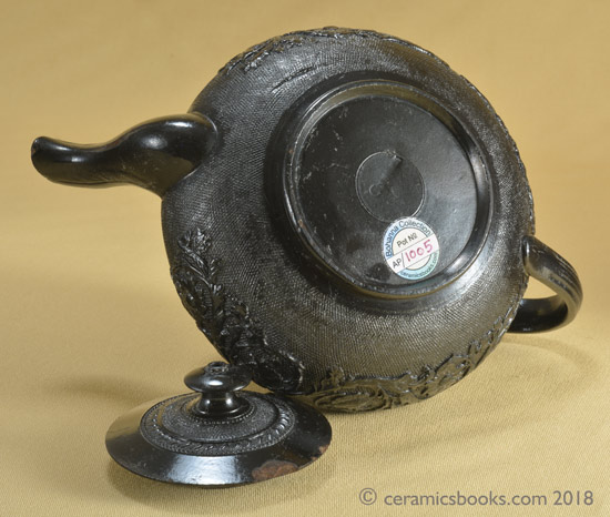 Small low-round black basalt teapot with floral sprig frieze on gauze background, marked CYPLES. Base. AP/1005