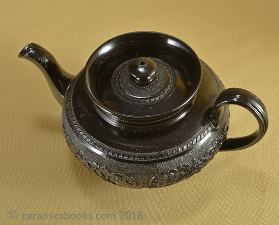 Small low-round black basalt teapot with floral sprig frieze on gauze background, marked CYPLES. Top. AP/1005