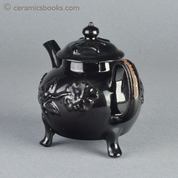 Shining Black 'Jackfield' type teapot on 3 feet with applied vine leaf and flower sprigs c.1755-1765. Back angle. AP/1240.