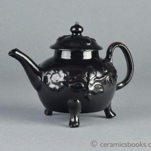 Shining Black 'Jackfield' type teapot on 3 feet with applied vine leaf and flower sprigs c.1755-1765. Obverse. AP/1240.