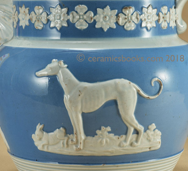 Pearlware blue ground jug with white clay sprigs including a greyhound, an eagle and a stag. Greyhound dog sprig. AP/722.