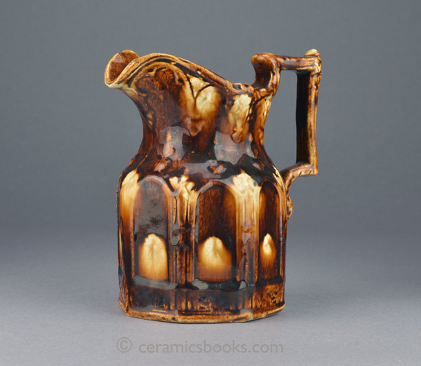 Two-tone treacleware moulded jug with Gothic arches. Obverse front. AP/888.