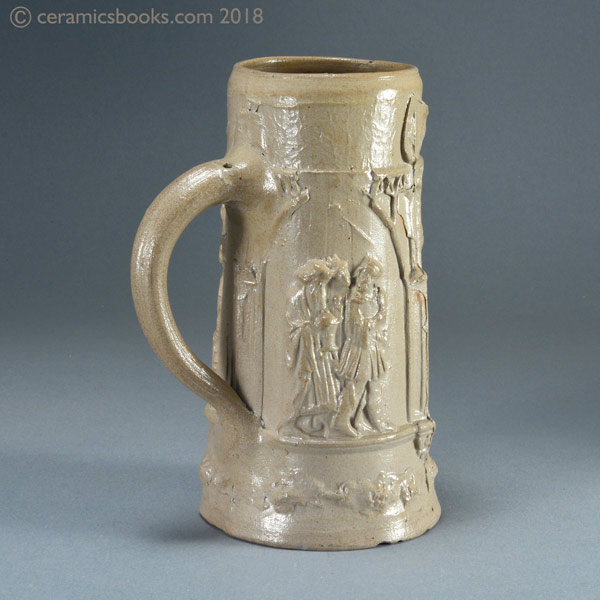 A grey / brown salt-glazed German stoneware stein with figures. C19th. Reverse angle. AP/992.
