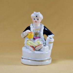An inkwell in the form of a Turkish man wearing a turban, sitting cross-legged. Decorated with both under-glaze and over-glaze colours. Staffordshire. Front.