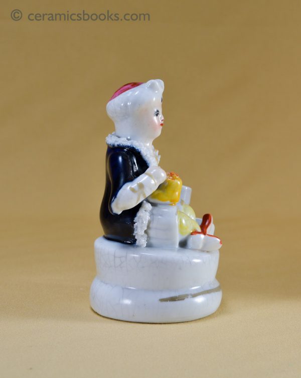 An inkwell in the form of a Turkish man wearing a turban, sitting cross-legged. Decorated with both under-glaze and over-glaze colours. Staffordshire. Right side.