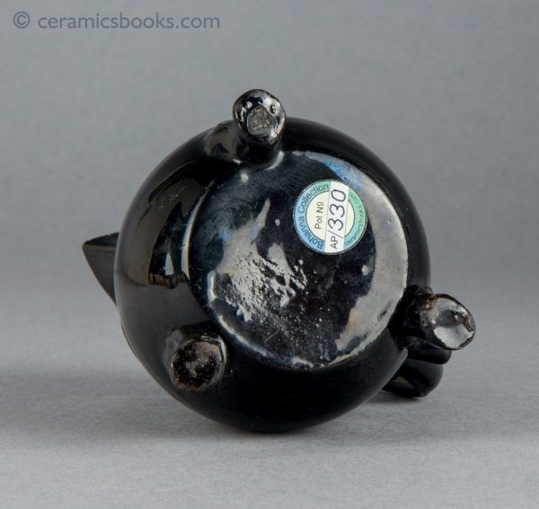 Small black-glazed 'Jackfield' type jug on three feet, with sparrow-beak spout. c.1755-1765. Base.