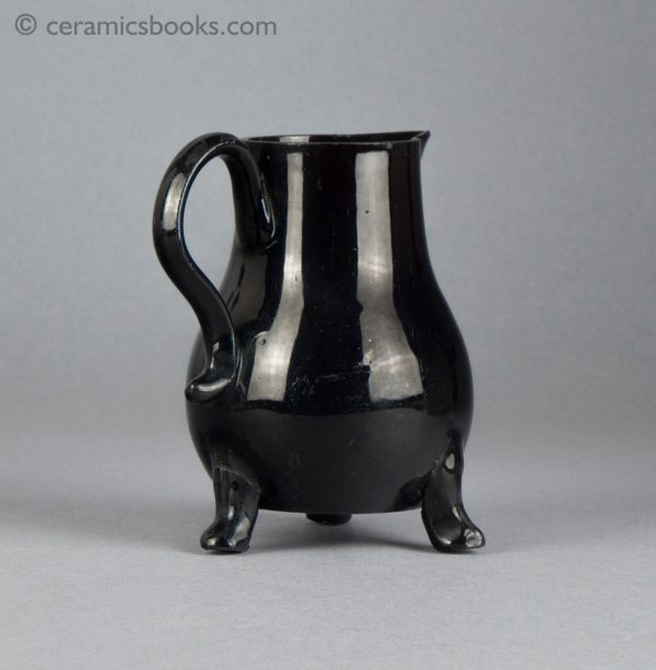 Small black-glazed 'Jackfield' type jug on three feet, with sparrow-beak spout. c.1755-1765. Back reverse.