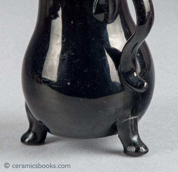 Small black-glazed 'Jackfield' type jug on three feet, with sparrow-beak spout. c.1755-1765. Close foot.