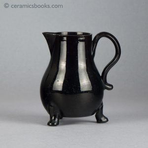 Small black-glazed 'Jackfield' type jug on three feet, with sparrow-beak spout. c.1755-1765. Obverse.