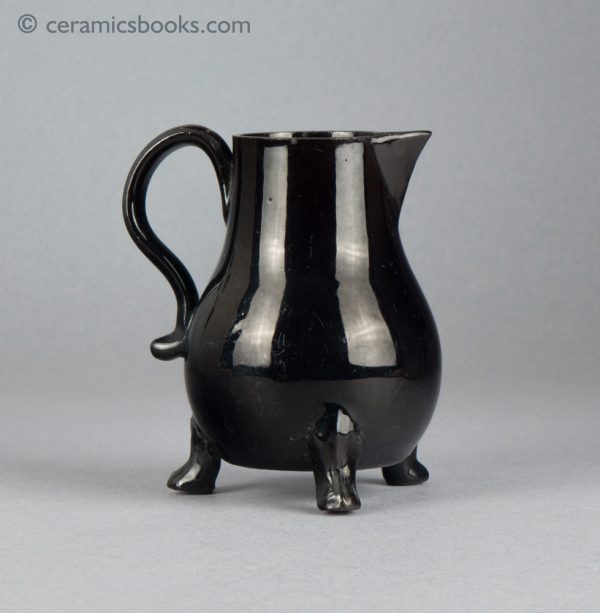 Small black-glazed 'Jackfield' type jug on three feet, with sparrow-beak spout. c.1755-1765. Reverse.