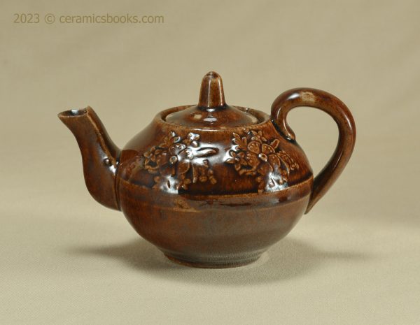Treacleware child size teapot with moulded flowers. c.1860-1885. AP/195. Obverse.