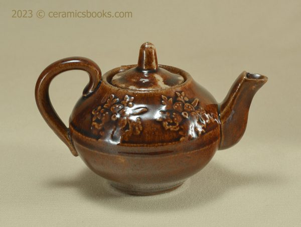 Treacleware child size teapot with moulded flowers. c.1860-1885. AP/195. Reverse.