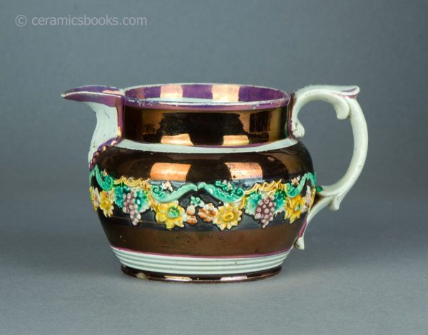 Pearlware jug with pink and copper lustre decoration, and enamelled flower sprigs. c.1820-1830. AP/1474. Obverse.