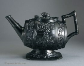 Glazed black basalt barrel shape teapot with grapevine moulding. An oddly incongruous design for a teapot. Staffordshire c.1825-1845. AP/483.